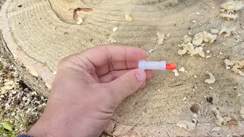 Sealed herbicide treatment plug held above a drilled tree stump.